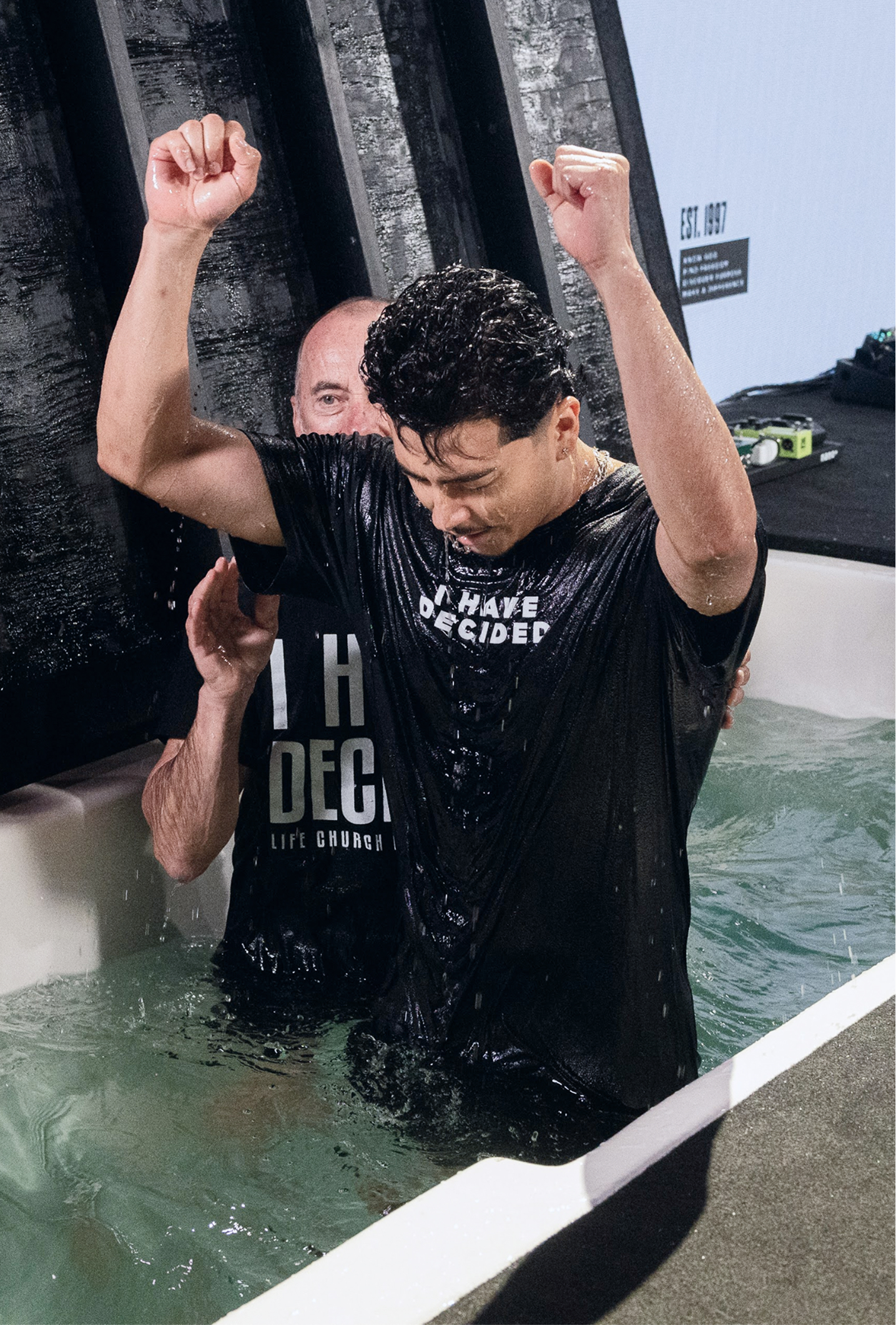A man celebrating his baptism with both fists raised